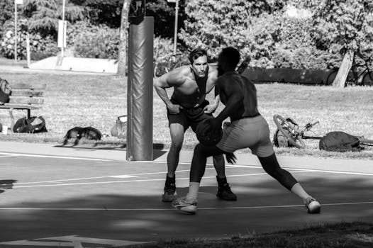 Two athletes engage in a competitive basketball game on an outdoor court.