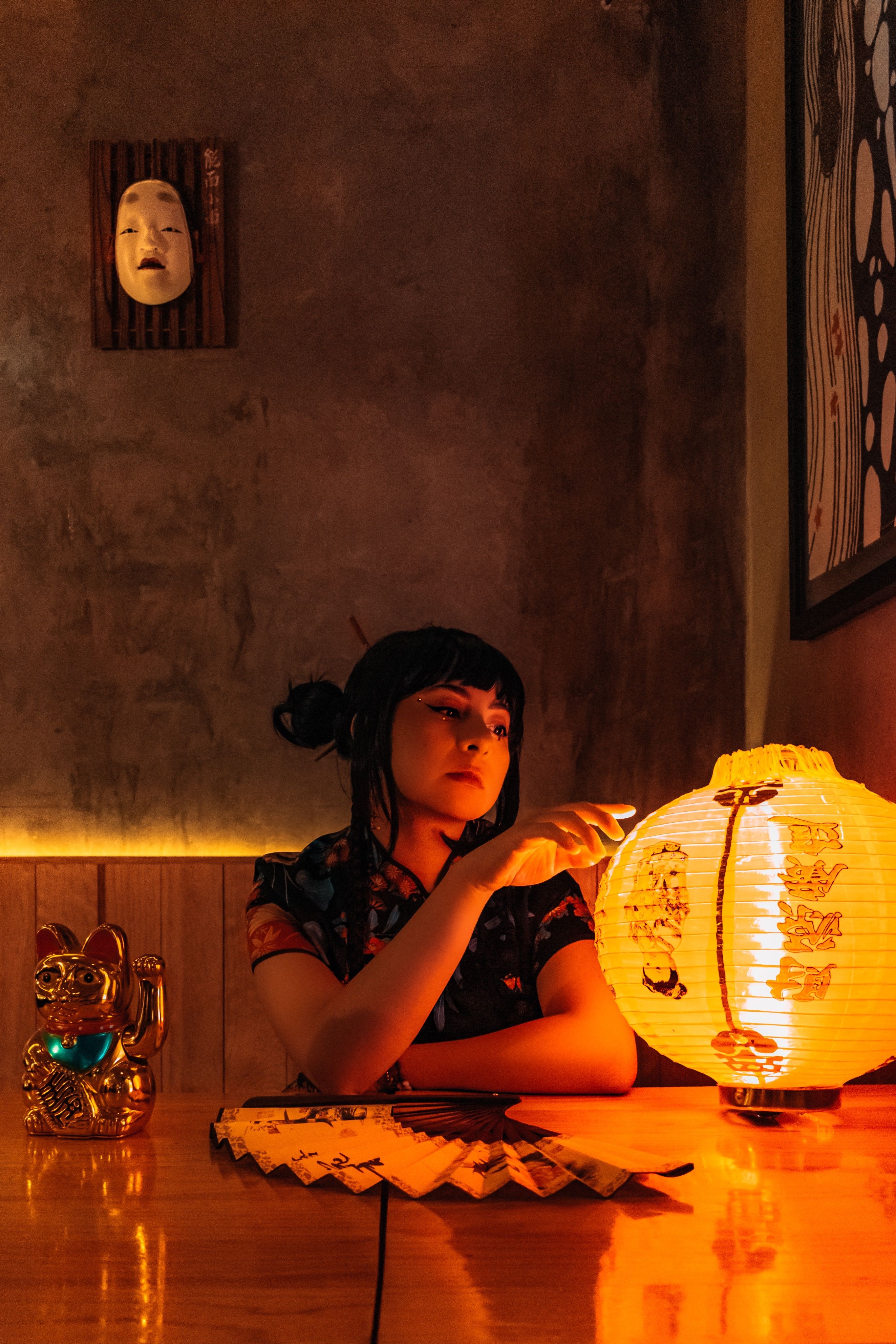 Young woman in a traditional setting lit by a Chinese lantern inside.