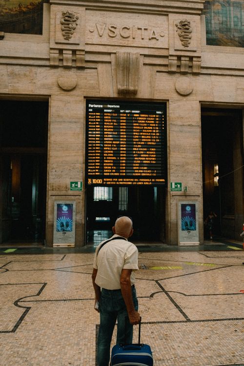 Free Senior man looking at schedule board in Milano Centrale Station with suitcase. Stock Photo