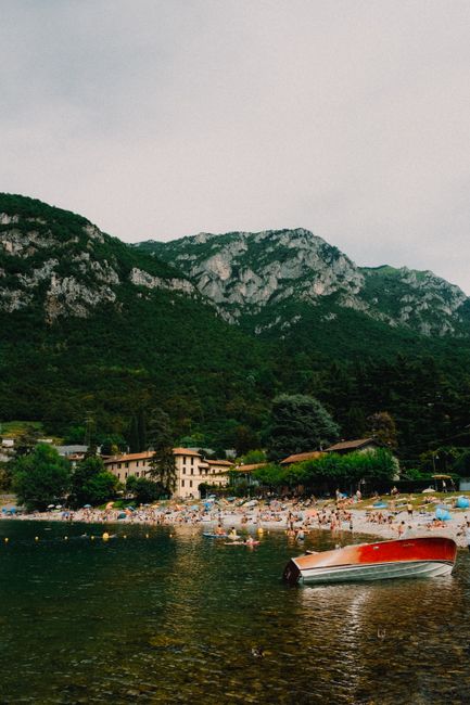 Crowded beach along a serene mountain lake in summer.