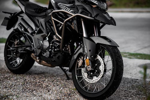 Free Detailed view of a black motorcycle parked on a gravel road. Stock Photo