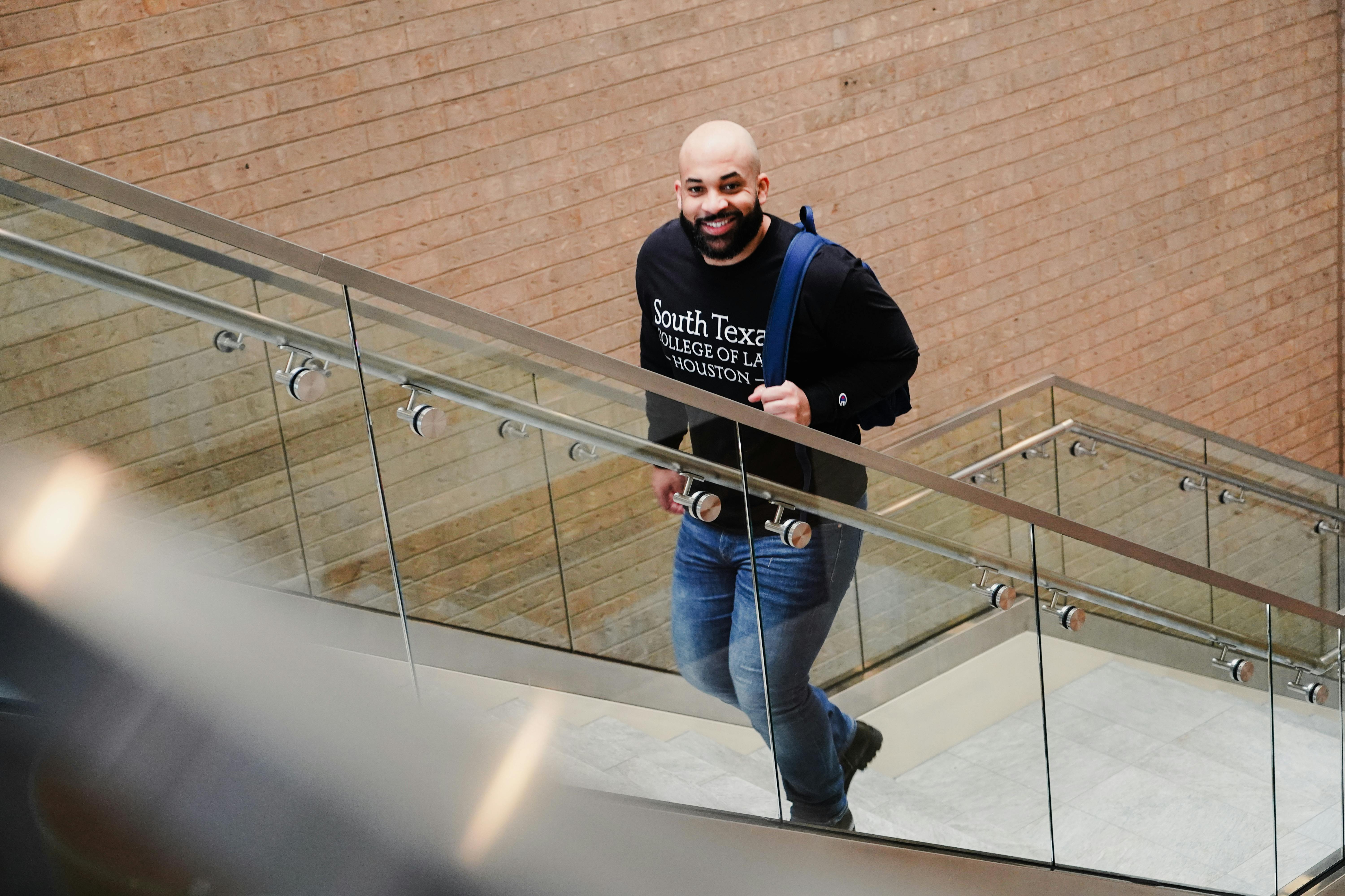 A student confidently ascends steps inside South Texas College of Law building.