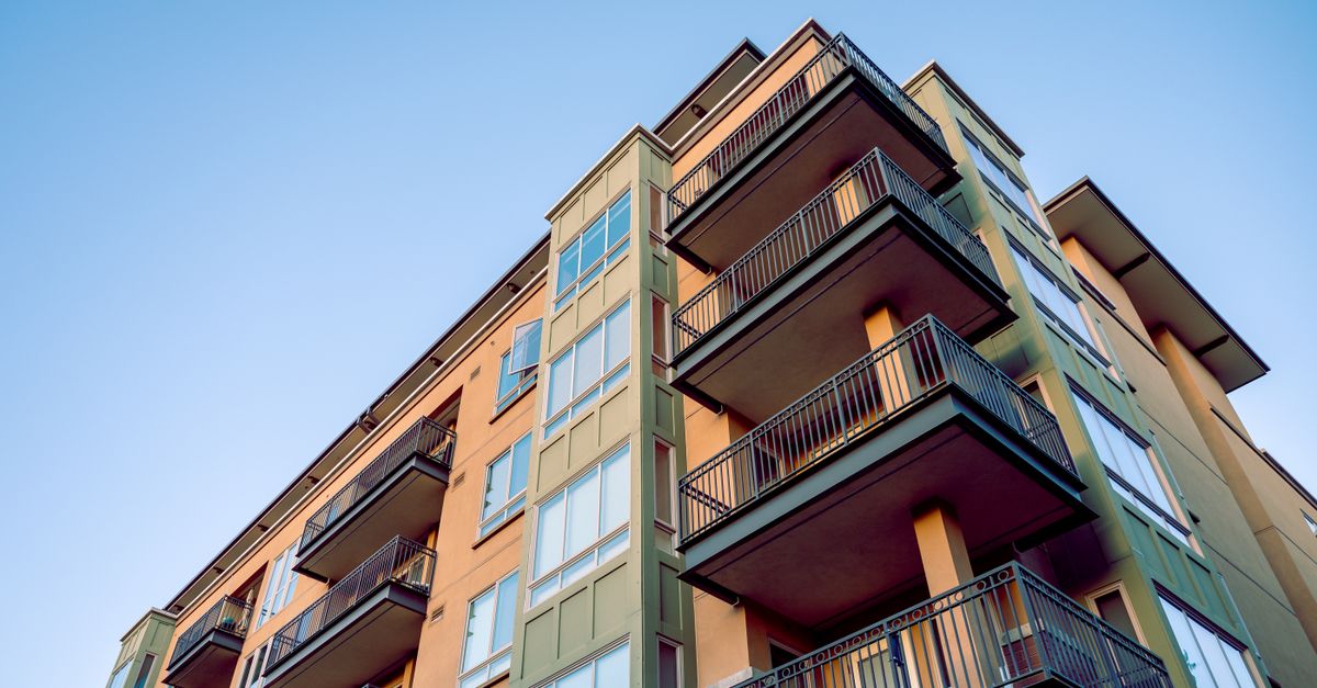 Contemporary city apartment building with multiple balconies and glass windows.
