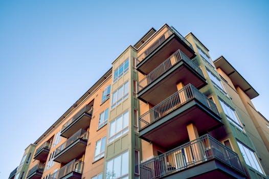 Contemporary city apartment building with multiple balconies and glass windows.