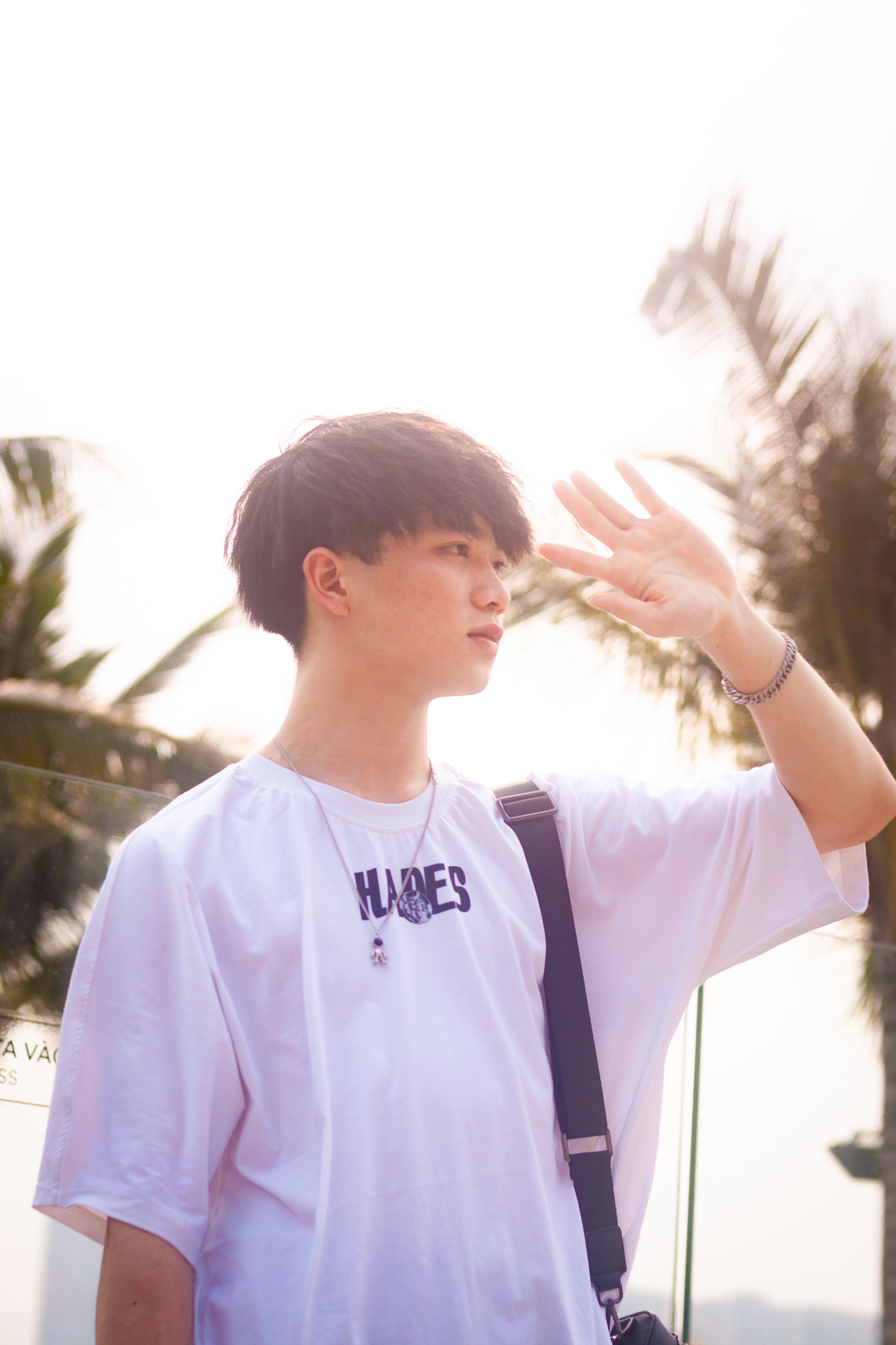 Portrait of a young Asian man in streetwear, basking in the summer sun outdoors in Hanoi.