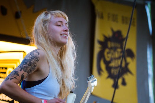 Dynamic capture of a female guitarist with tattoos playing live at a summer festival.