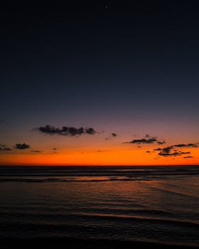 A beautiful sunset over the seascape in Acapulco, Mexico, featuring vivid orange hues and gentle waves.