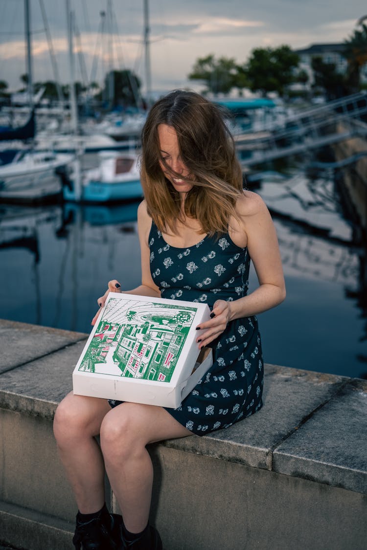 A Woman In A Sleeveless Dress Opening A Box