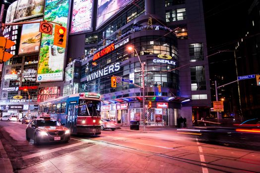 Bustling street scene in Toronto with vibrant lights, traffic, and urban energy at night.