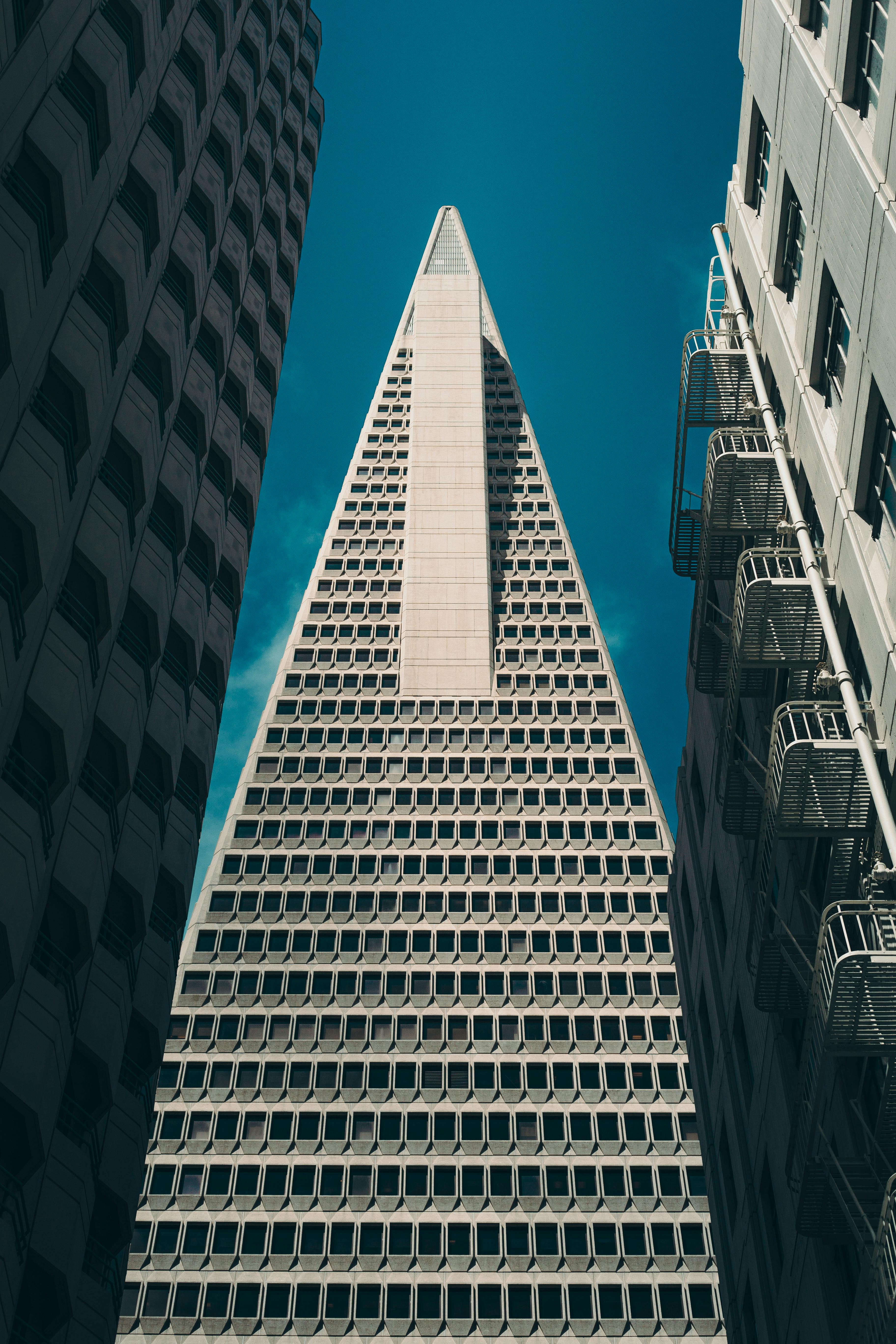 Vertical view of the iconic Transamerica Pyramid framed by surrounding buildings against a clear blue sky.