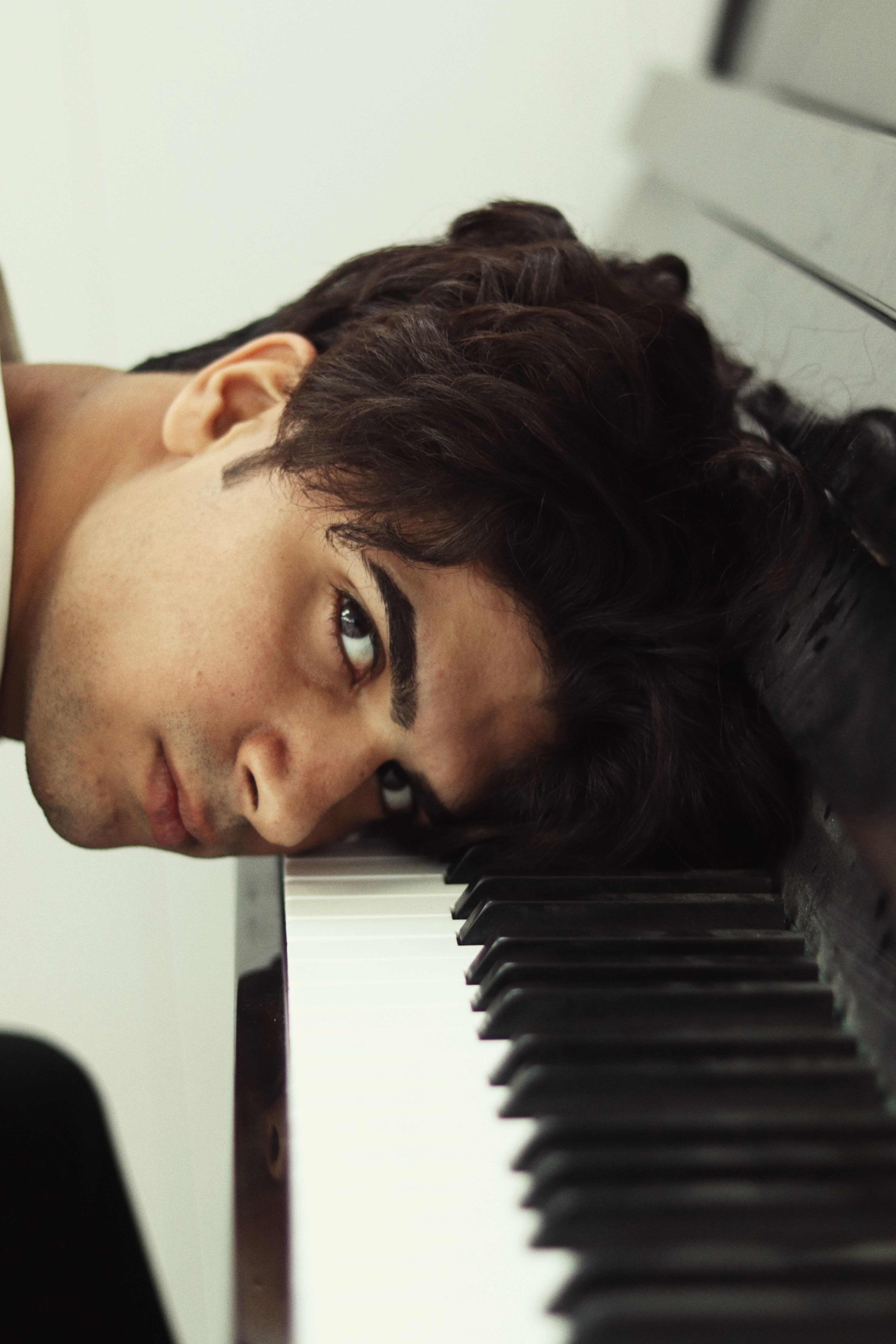 A man resting his head on a piano keyboard, capturing a musical moment.