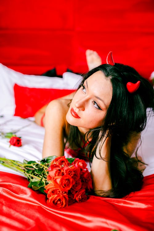 Sexy Brunette in Lingerie Lying in Bed with Roses
