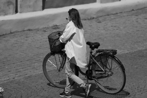 Free A woman walks her bicycle on a cobblestone street in Jönköping, Sweden, in black and white. Stock Photo