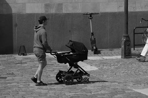 A Grayscale of a Man Pushing a Baby Stroller