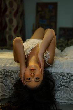 Sultry woman posing gracefully on a bed in lacy lingerie for an intimate photoshoot.