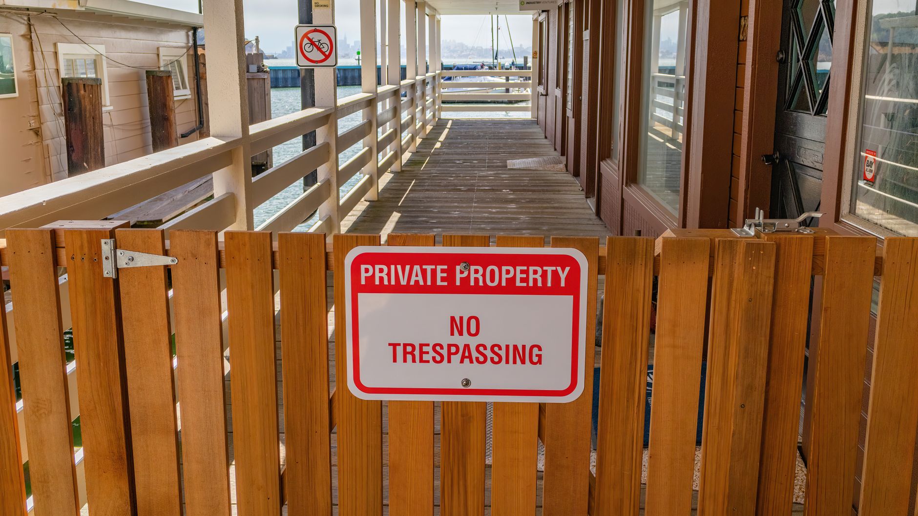 Wooden gate with a private property no trespassing sign in an outdoor setting.