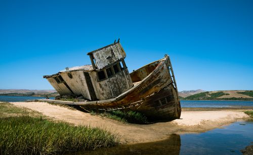 Free Abandoned shipwreck on the sandy shores of Tomales Bay under a clear blue sky. Stock Photo