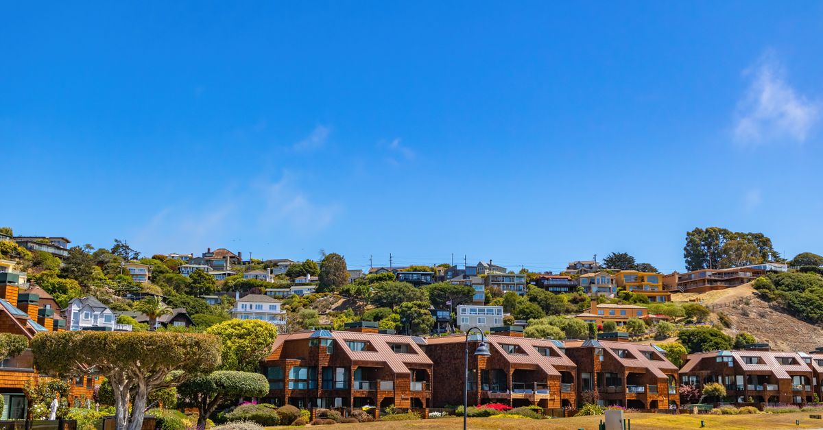 Idyllic hillside neighborhood with modern houses under a bright blue sky.