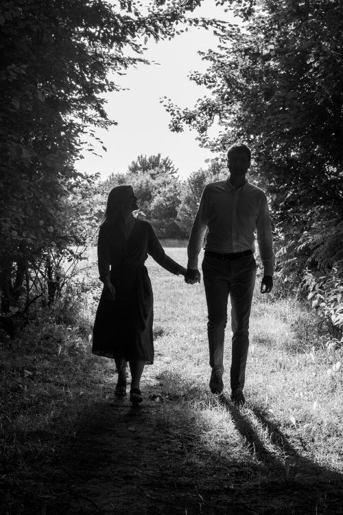Free Black and white silhouette of a couple walking through a forest pathway, symbolizing love and togetherness. Stock Photo