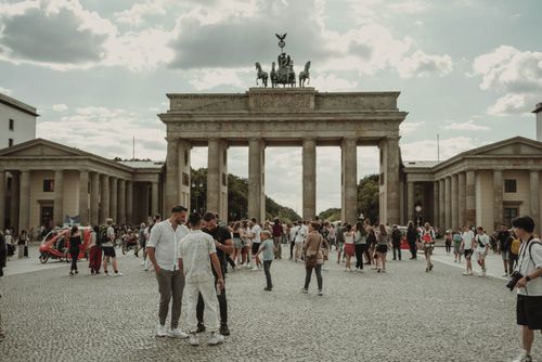 Free Enjoy a bustling scene at Berlin's iconic Brandenburg Gate, filled with a diverse crowd on a sunny day. Stock Photo