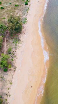 A calm sandy beach with gentle waves captured from above, showcasing serene coastal beauty.