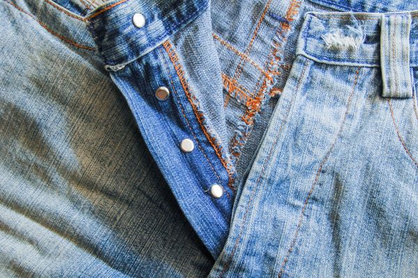 Close-up of a button fly on mid-wash jeans