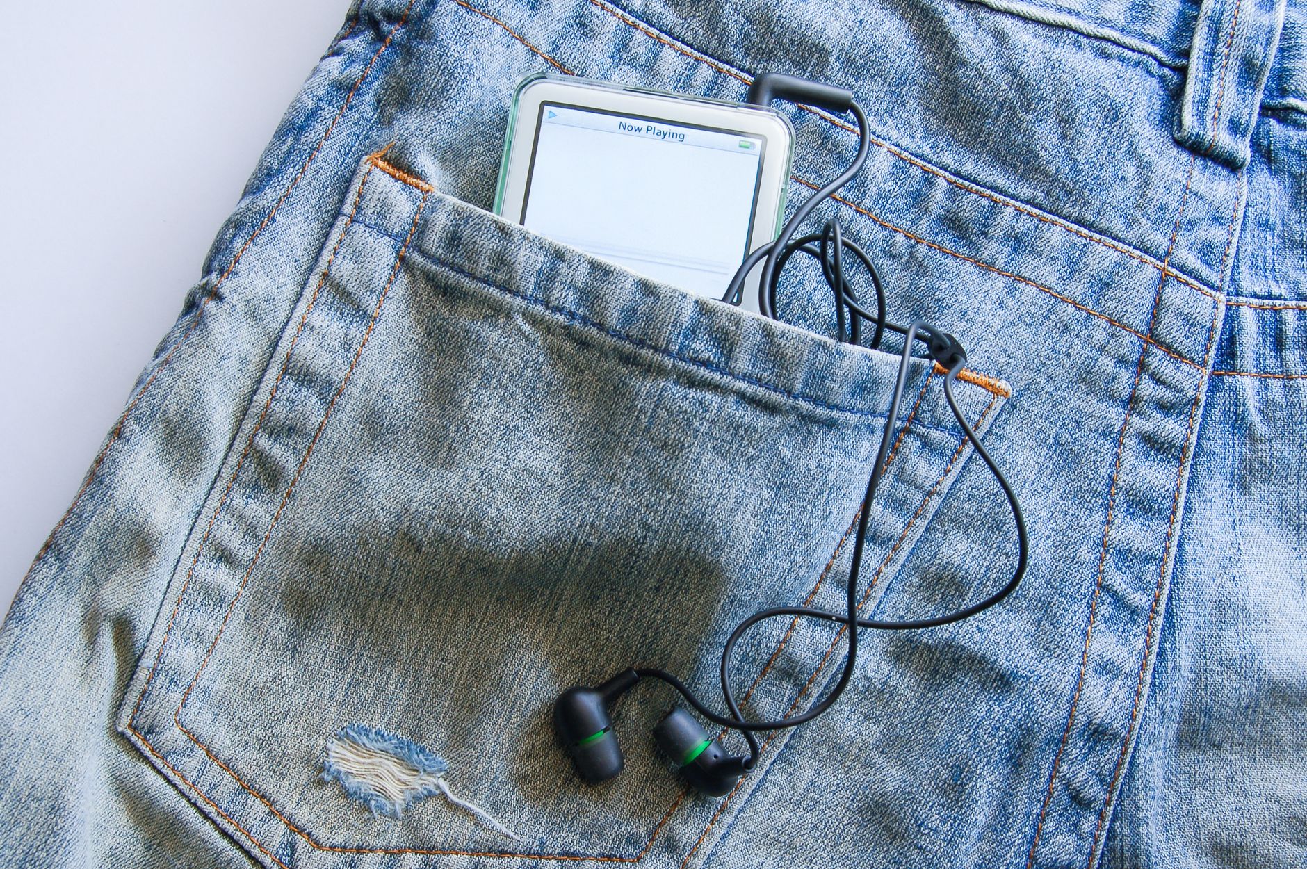 Modern smartphone with earphones in blue denim pocket, showcasing casual lifestyle.