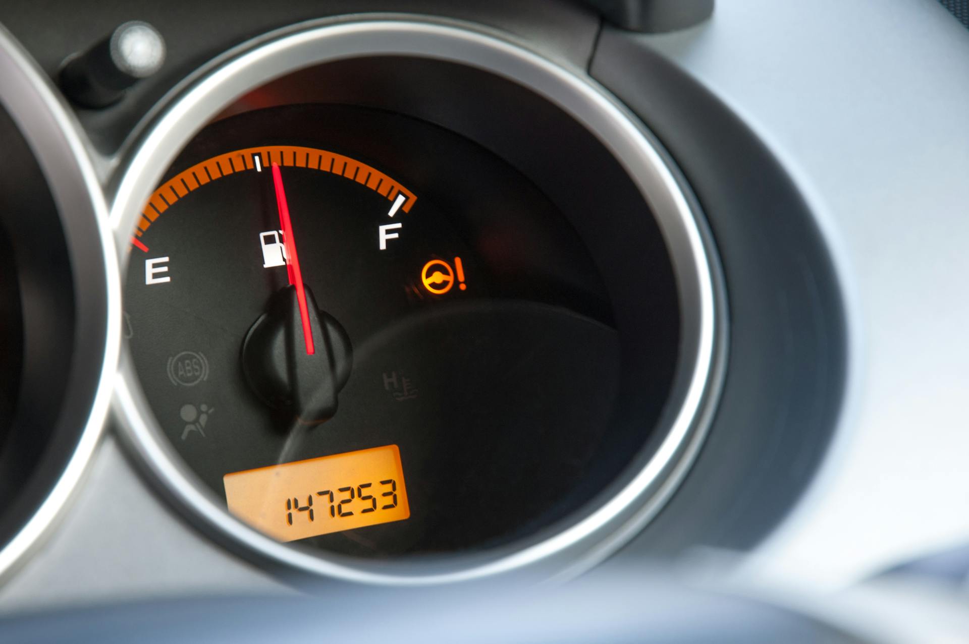 Detailed close-up of a car's fuel gauge with odometer showing a reading of 147253 miles.