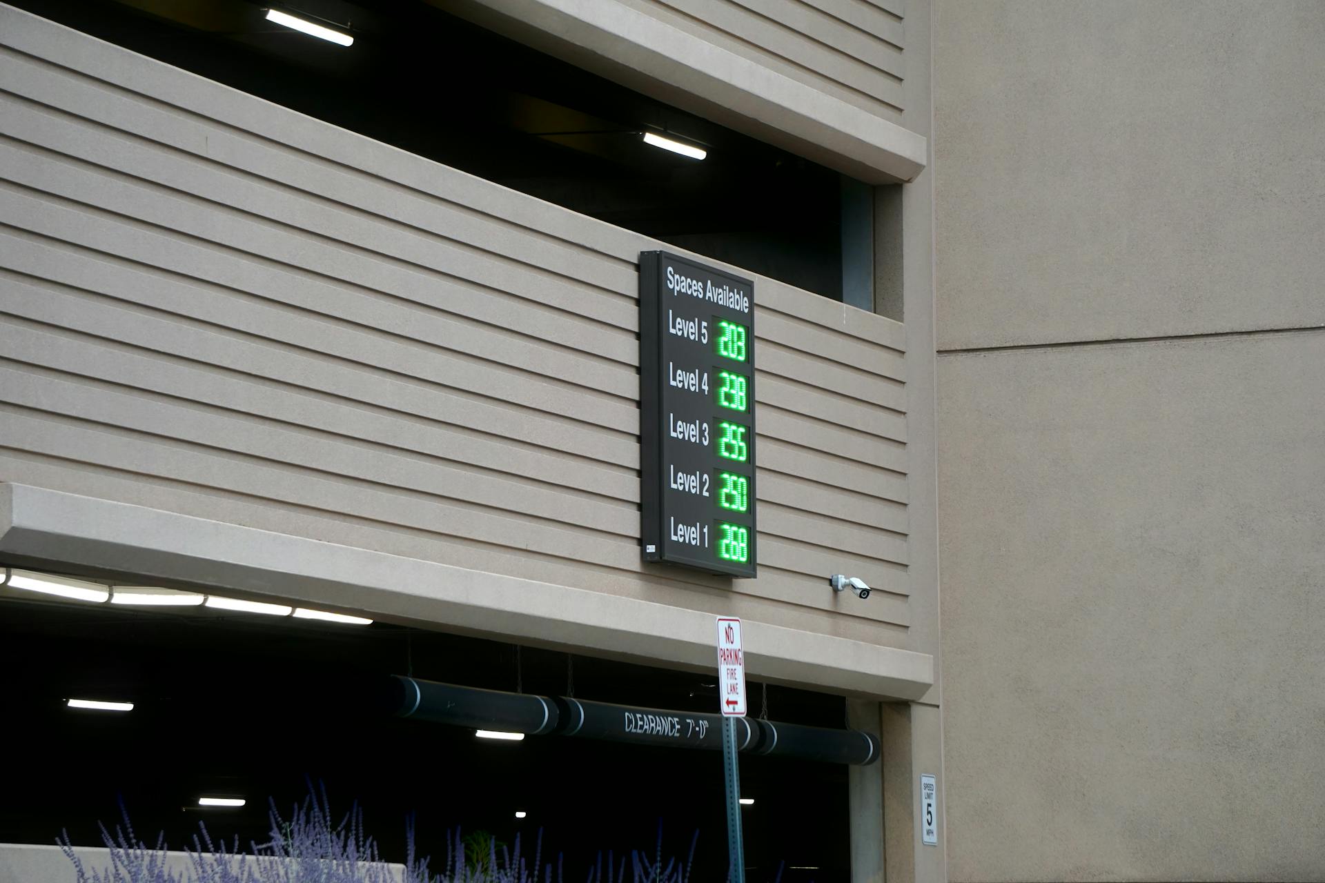 An outdoor parking garage with digital signage displaying available spaces for each level.