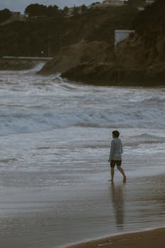 A person walks along a stormy beach, capturing a moody coastal scene.