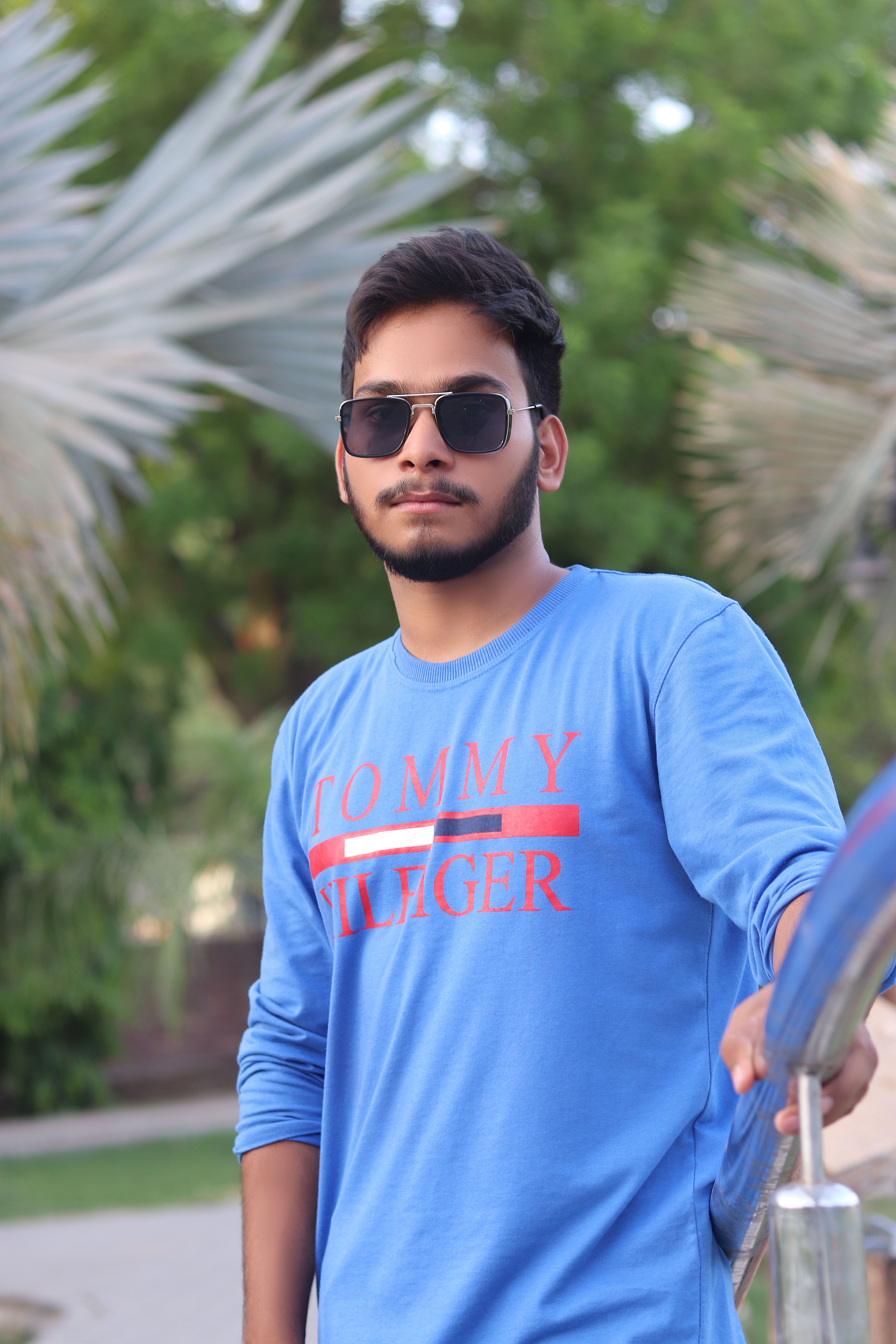 Portrait of a young man in sunglasses and blue sweater outdoors.