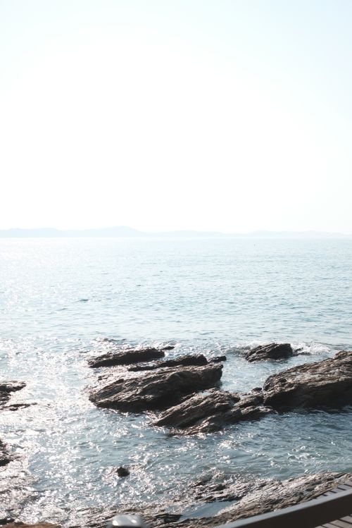 Free Sunlit rocks along the serene Thai coastline in Phe, Rayong, with sparkling ocean waves. Stock Photo