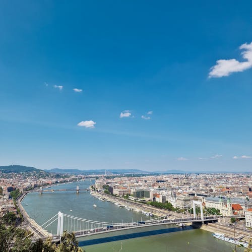 Aerial Photography of White Bridge Above Danube River Near City Buildings Under Blue Sky