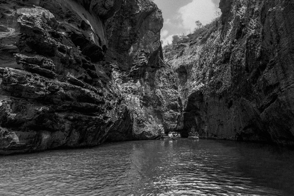 Explore the tranquility of a river flowing through majestic cliffs in monochrome.