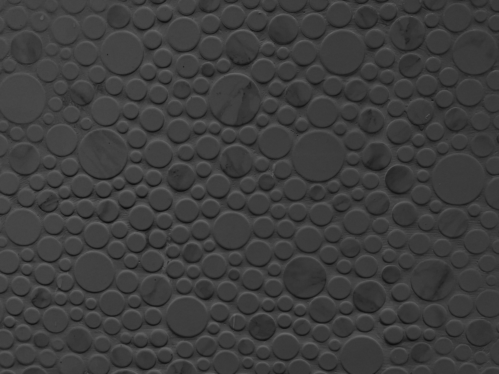 Seamless textured pattern with dark gray circles on a grey background, ideal for design and decoration.