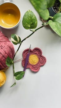 Handmade crochet flower and yarn with crochet hook on a white background.