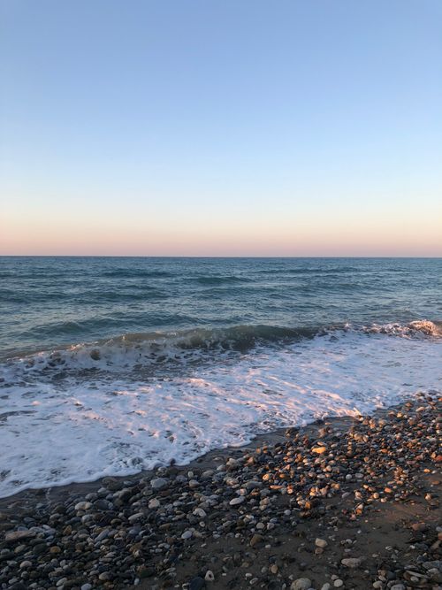 Free Gentle waves crash on a rocky shoreline during twilight, offering a serene seascape. Stock Photo
