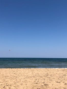 A peaceful seaside view with a vast blue sky and sandy beach, perfect for relaxation.