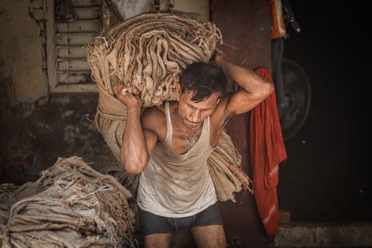 A man in Ballia, India, carrying heavy fabric bundles, showcasing hard work and determination.