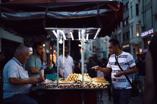 Free Street vendor offering fresh snacks to customers on a lively evening in Istanbul, Turkey. Stock Photo