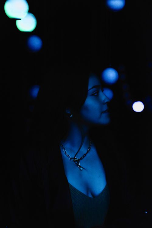 Free Artistic nighttime portrait with blue lighting and bokeh effect, showcasing mood and style. Stock Photo