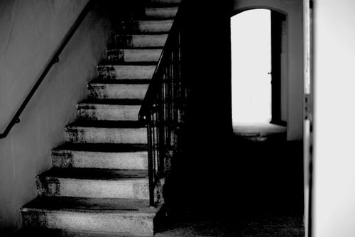Free A dramatic black and white photo of an interior staircase under dim light. Stock Photo
