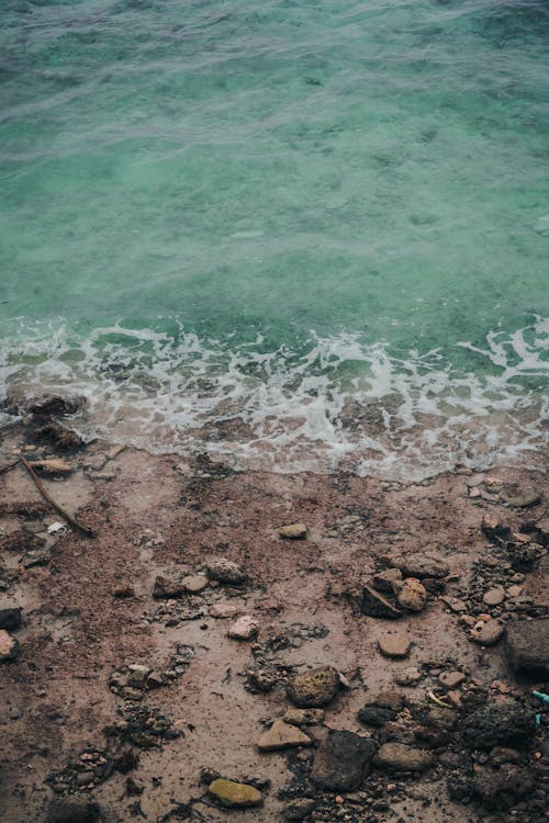 A High Angle Sot of Rocks on Brown Sand Beside Body of Water