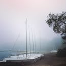 雾霭笼罩的海滩上，帆船静静排列，呈现出一派宁静祥和的景象