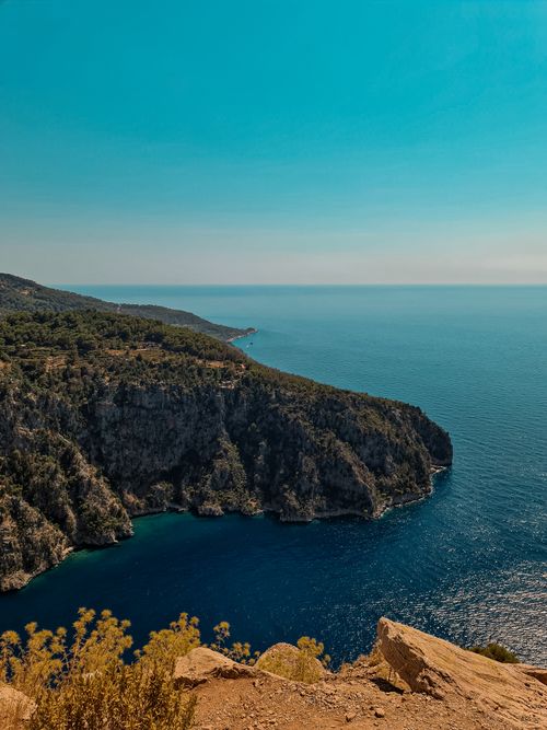 Free Stunning cliffside view of turquoise ocean waters under bright blue sky. Ideal for travel and nature themes. Stock Photo