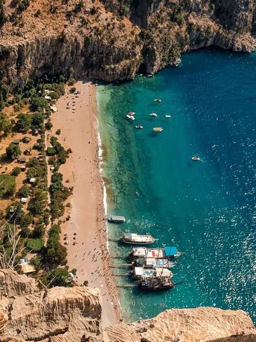 Free A breathtaking aerial shot capturing Butterfly Valley's pristine beach, turquoise waters, and docked boats. Stock Photo