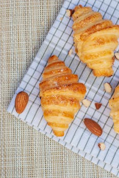 Tasty golden croissants and almonds beautifully arranged on a checkered cloth.