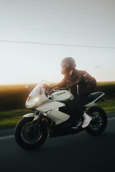 Motorcyclist on a Kawasaki motorbike cruising along a scenic outdoor road at daytime.