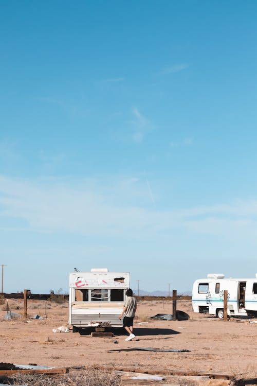 Person Standing outside an Abandoned Trailer on a Desert