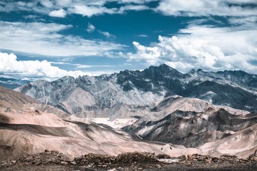 Breathtaking view of rugged mountains under a vibrant, cloud-filled sky.